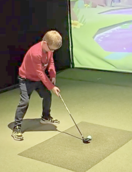 Black Polo Golf youth golfer training indoors with simulator feedback